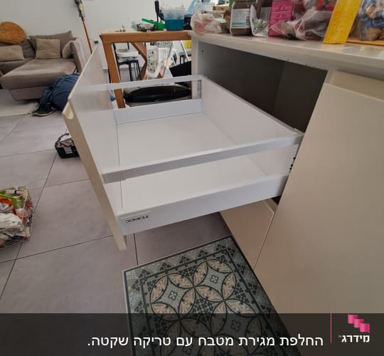 מגירת מטבח לבנה פתוחה עם מוצרים על השיש